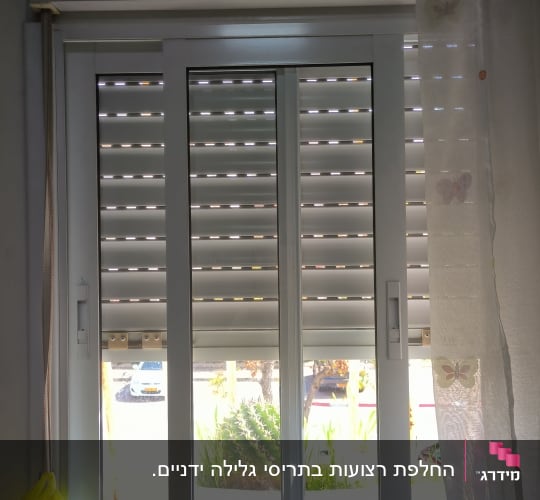 תריסים לבנים סגורים עם חריצים לאור